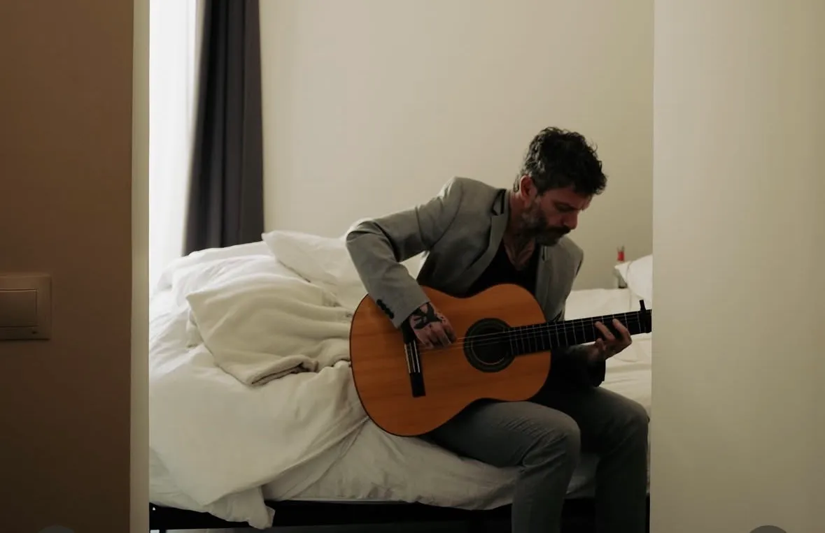 Juan Medina sentado con la guitarra flamenca sobre la pierna, mirando al frente
