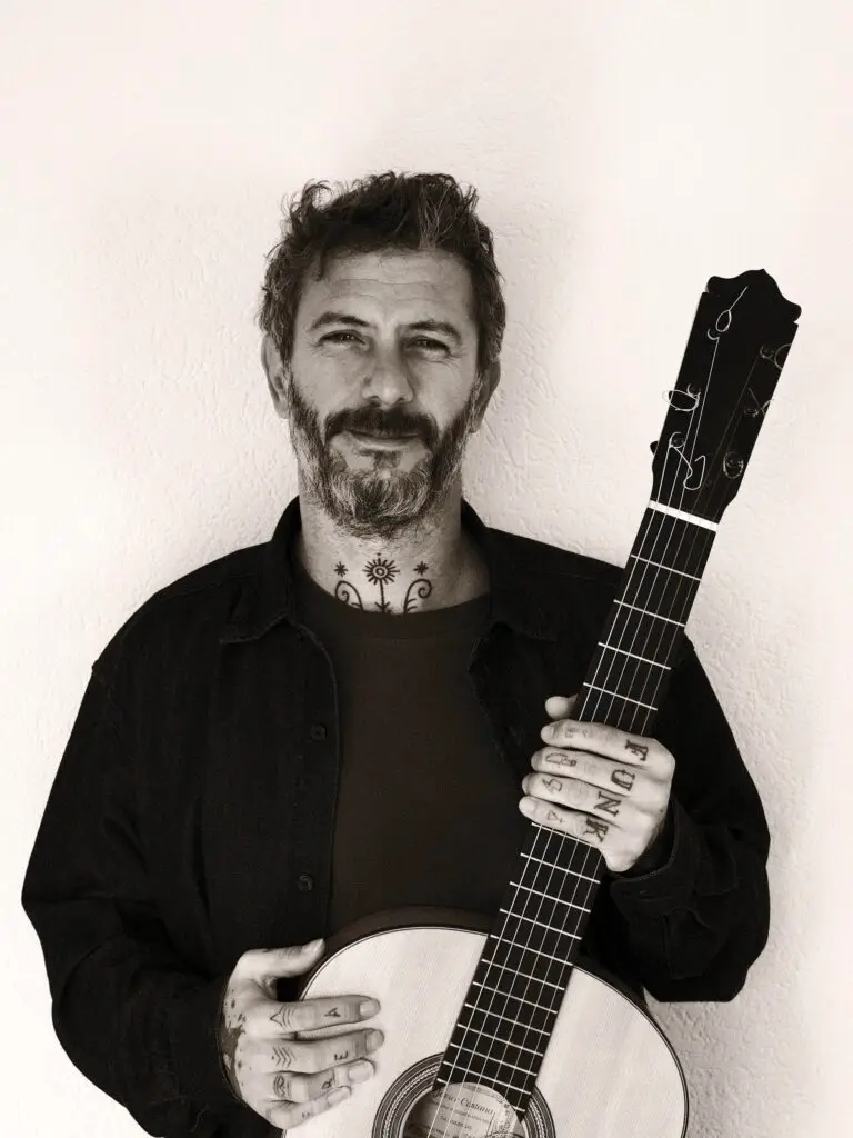 Juan Medina seated with the flamenco guitar on his knee, looking ahead